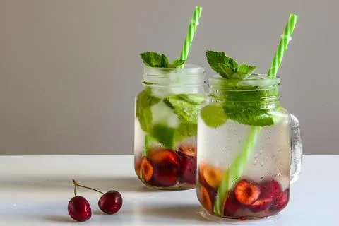 Cold drinks in small bottles. Cherries mint lemonade. Mojito coctail. Stock Photos