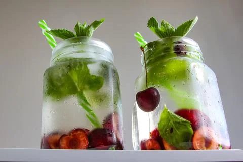 Cold drinks in small bottles. Cherries mint lemonade. Mojito coctail. Stock Photos