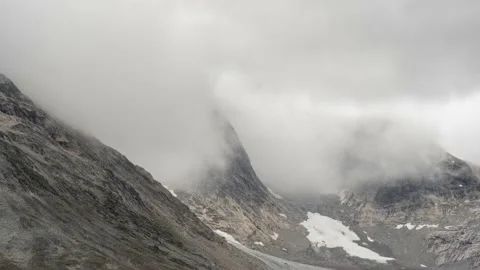Cold fog and clouds rush over and down rocky steep mountain slopes. Time Stock Footage 151872300