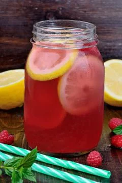 Cold fresh raspberry lemonade in a glass jar on table Stock Photos