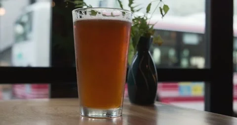 A cold glass of beer next to a window in a city Stock Footage 236596396