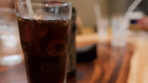 Cold Glass of Cola with Ice Cubes on Wooden Restaurant Table Stock Footage 345219802