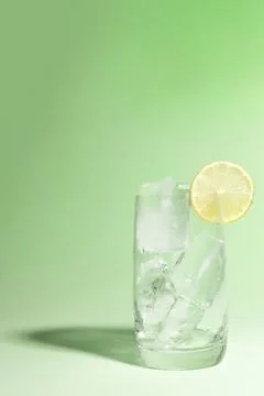 Cold glass full of ice with a lime, ready to serve light green with cast shadow. Stock Photos