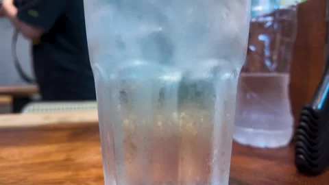 Cold Glass of Sparkling Water with Ice Cubes on Wooden Table Video stock 341925115