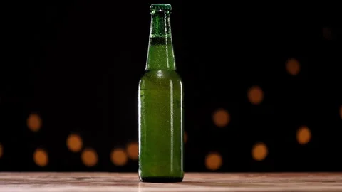 Cold green refrigerated wheat or lager beer bottle, condensation droplets cover Stock Footage 331423842