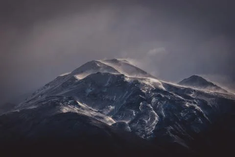 Cold grey clouds over a rugged mountain Stock Photos