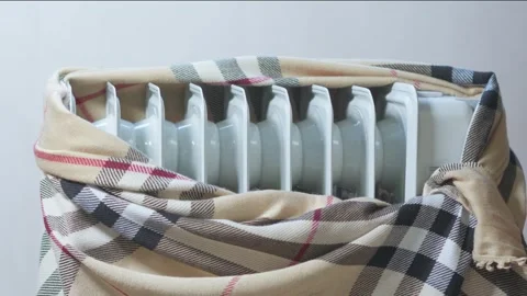 A cold heating radiator is wrapped in a woolen blanket for warmth. Stock Footage 256071373