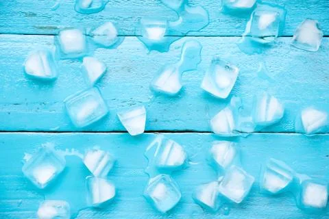 The cold ice cubes are partial melt on blue wood background Stock Photos