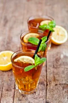 Cold iced tea with lemon, mint leaves and ice cubes in three glasses on rusti Stock-Fotos