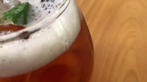 Cold iced tea in a rounded glass, topped with foam and fresh mint, with a b.. Stock Footage 322925587