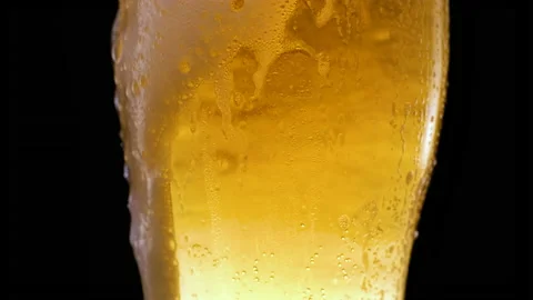 Cold light beer in a beer mug on black background with water droplets and foam Stock Footage 154739223