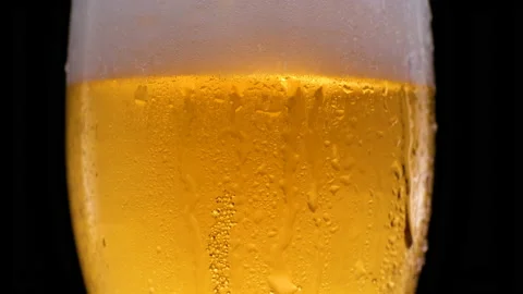 Cold light beer in a beer mug on a black background with water droplets and foam Stock Footage 155686482