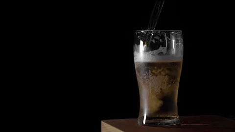 Cold Light Beer is poured into a glass with water drops ever matte black Stock Footage 113053403