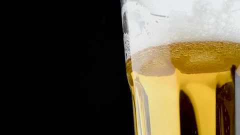 Cold light craft beer is poured into a glass. Close-up video on a black backgrou Stock Footage 146155010