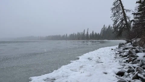 Cold looking scene with falling snow over a large partially frozen lake  Stock Footage 249839100