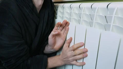 Cold Man in Bathrobe Warms Hands on Central Heating Radiator Stock Footage 329402969