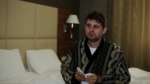 Cold man sneezes into his handkerchief. The man sneezes in the bedroom. Stock Footage