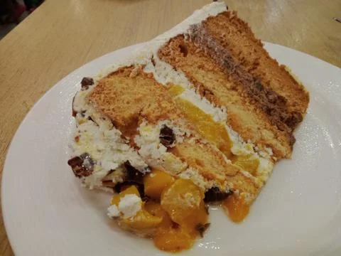 COLD MANGO CREAM CAKE SERVED ON A WHITE PLATE PLACED ON A WOODEN TABLE Stock Photos