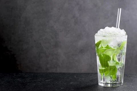 Cold mojito with lime and mint leaves on black table Фото