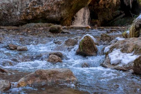 Cold mountain river flows between stones with snow and ice, selective focus,  Stock Photos