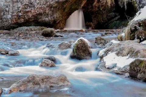 Cold mountain river flows between stones with snow and ice, selective focus,  Stock Photos