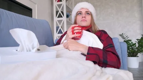 Cold or disease concept. Young woman lying on a sofa covered with a white plaid Видео 142837451