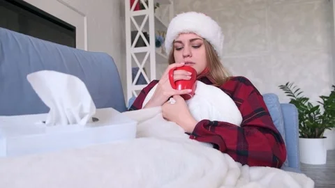 Cold or disease concept. Young woman drinking hot tea or medicine lying on sofa Stock Footage 142935817