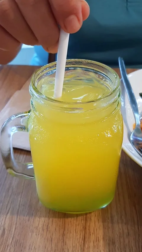 Cold Orange Mango Citrus Juice Stirred with Ice Cubes in Glass at Bright Café Stock Footage 312625106