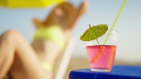 Cold pink cocktail served at a beach bar with a blurred vacationer relaxing.. Stock Footage 341342916