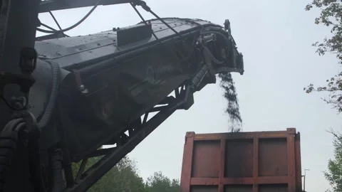 Cold planer or milling machine dumping ground asphalt into truck Stock Footage 158050454