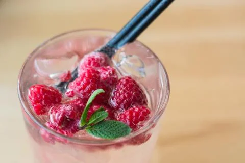Cold raspberry drink with mint leaves in a sweaty glass on a table in a cafe Stock Photos