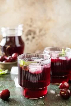 Cold refreshing cherry cola in a glass with ice on a stone background, summ.. Stock Photos