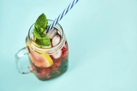 Cold refreshing cocktail with ice, mint and copy space on blue background. Fotos de archivo