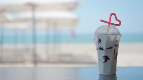 A cold refreshing drink against the backdrop of a brightly lit sea coast. Emp Stock Footage 157382242