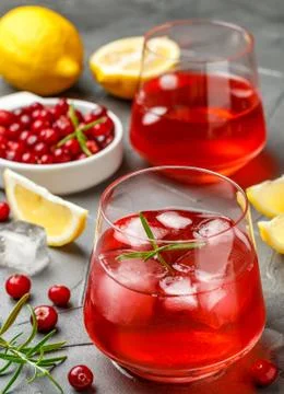 Cold refreshing drink of cranberry, lemon, rosemary and ice cubes Stock Photos