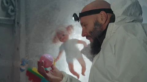 Cold researcher examines decayed toy artifacts. Bearded investigator explores Stock Footage 346522278