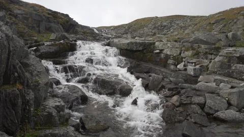 A cold river flows among stones, rocks and mountains. Water beats against stones Video stock 161867991
