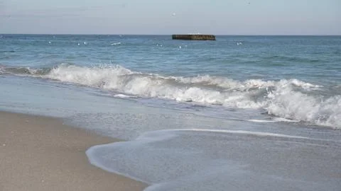 Cold sea waves crash with splashes on an empty sandy beach Stock Photos