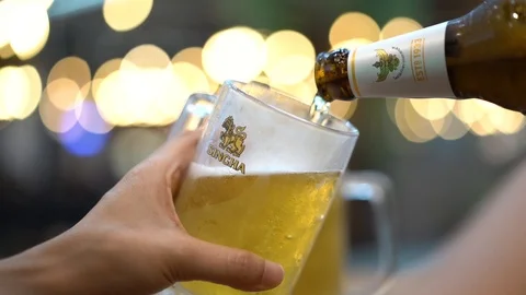 Cold singha beer pouring from beer bottle into beer mug, slow motion Stock Footage 106376146