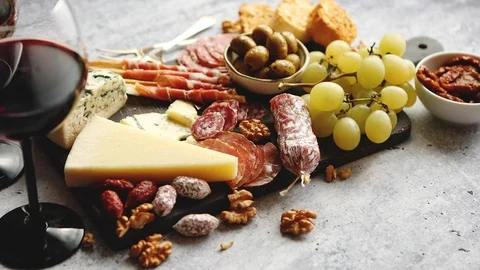 Cold snacks board with meats, grapes, wine, various kinds of cheese Stock Footage 97786409