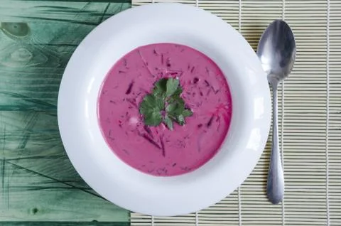 Cold soup of beetroot and vegetables with herbs on a white plate Stock Photos