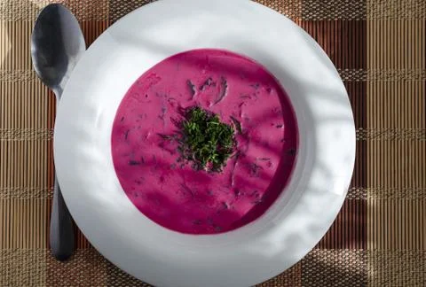 Cold soup of beetroot and vegetables with herbs on a white plate Stock Photos