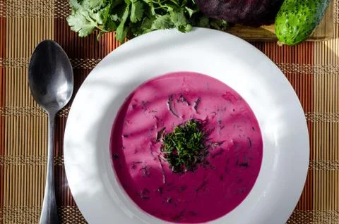 Cold soup of beetroot and vegetables with herbs on a white plate Stock Photos