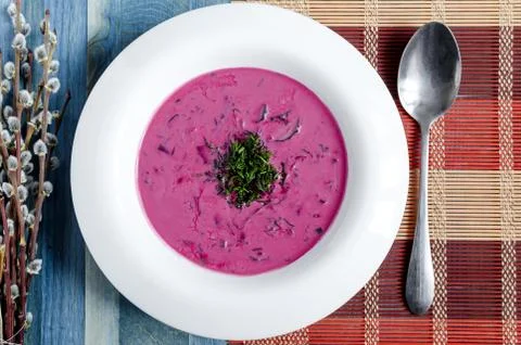 Cold soup of beetroot and vegetables with herbs on a white plate Stock Photos