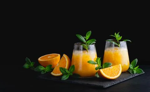 Cold summer orange lemonade with mint and ice in a glass. Copy Space for text Fotos Stock