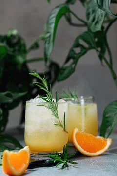 Cold summer refreshing orange and ice drink with a sprig of rosemary Stock Photos