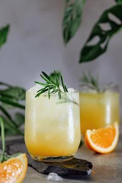 Cold summer refreshing orange and ice drink with a sprig of rosemary Stock Photos