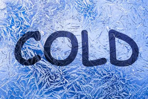 Cold text on frozen patterned glass.on winter window. Stock Photos
