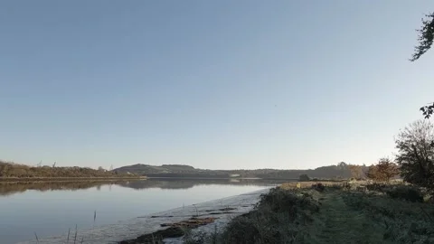 Cold tranquil morning river with tiny airplane flying through frame Stock Footage 164510740