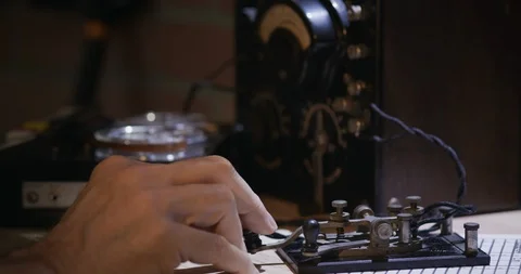 Cold war era spy sending morse code with tape recorder in background Stock Footage 108073570